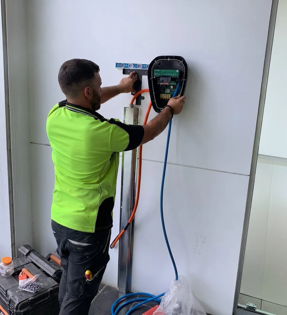 A Voltcore electrician levelling and wiring an EV charger on site